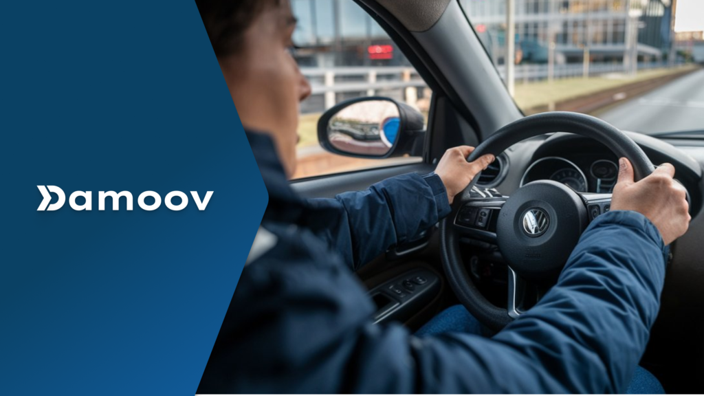 A driver grips the steering wheel of a car, with an urban environment visible through the window, symbolizing the role of mobile telematics in analyzing and improving driver behavior.
