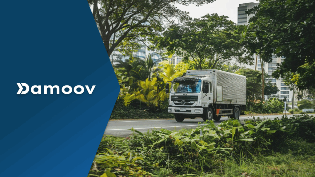 A white delivery truck drives along a green urban road with lush trees and city buildings in the background, symbolizing eco-friendly driving and sustainable fleet operations.