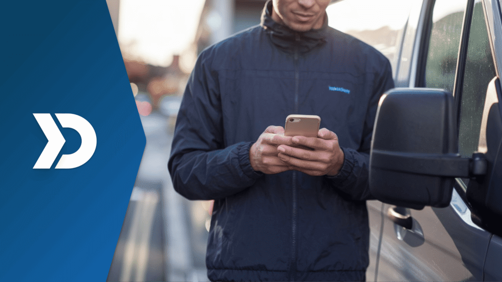 Delivery driver using a smartphone beside a commercial van to track safety scores, mileage, and driving performance with mobile telematics for delivery fleet management.