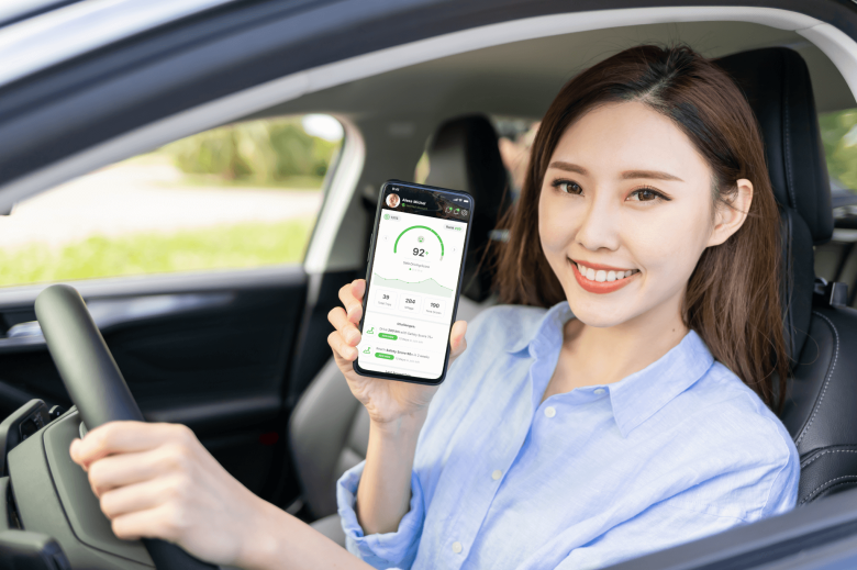 An employee driver with her hand on the stirring wheel shows her driver score in the Zenroad app for safe driving powered by Damoov.